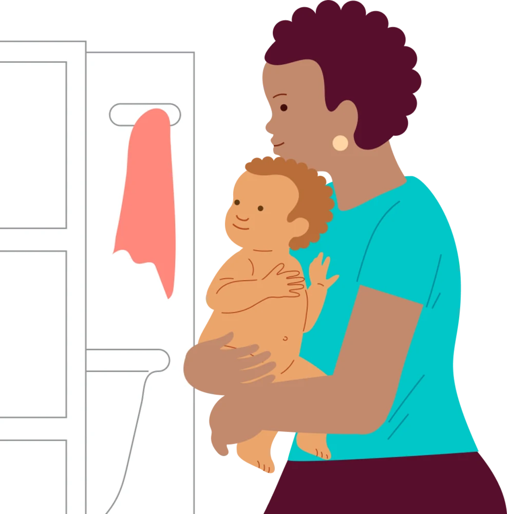 A caregiver holds a baby in a towel after bath time.