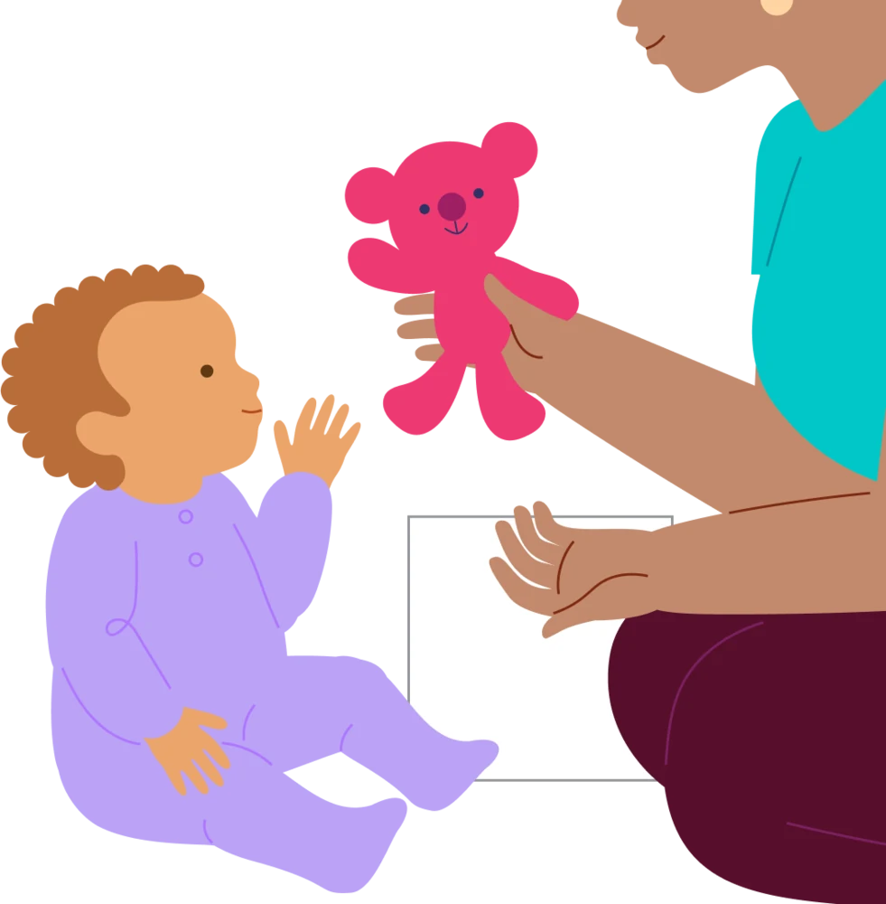 A baby reaches toward a toy while the caregiver waits for their response.